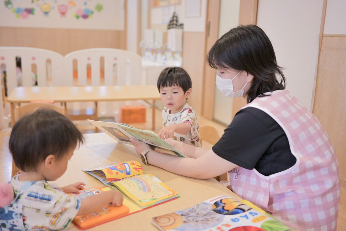 絵本を読む保育士と園児(ひよこルーム江戸川保育園)